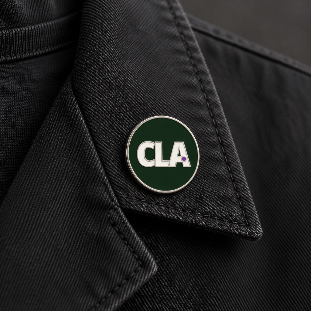 Digital mock-up: the 25 mm CLA enamel pin worn on a black jacket lapel; clothing not included.